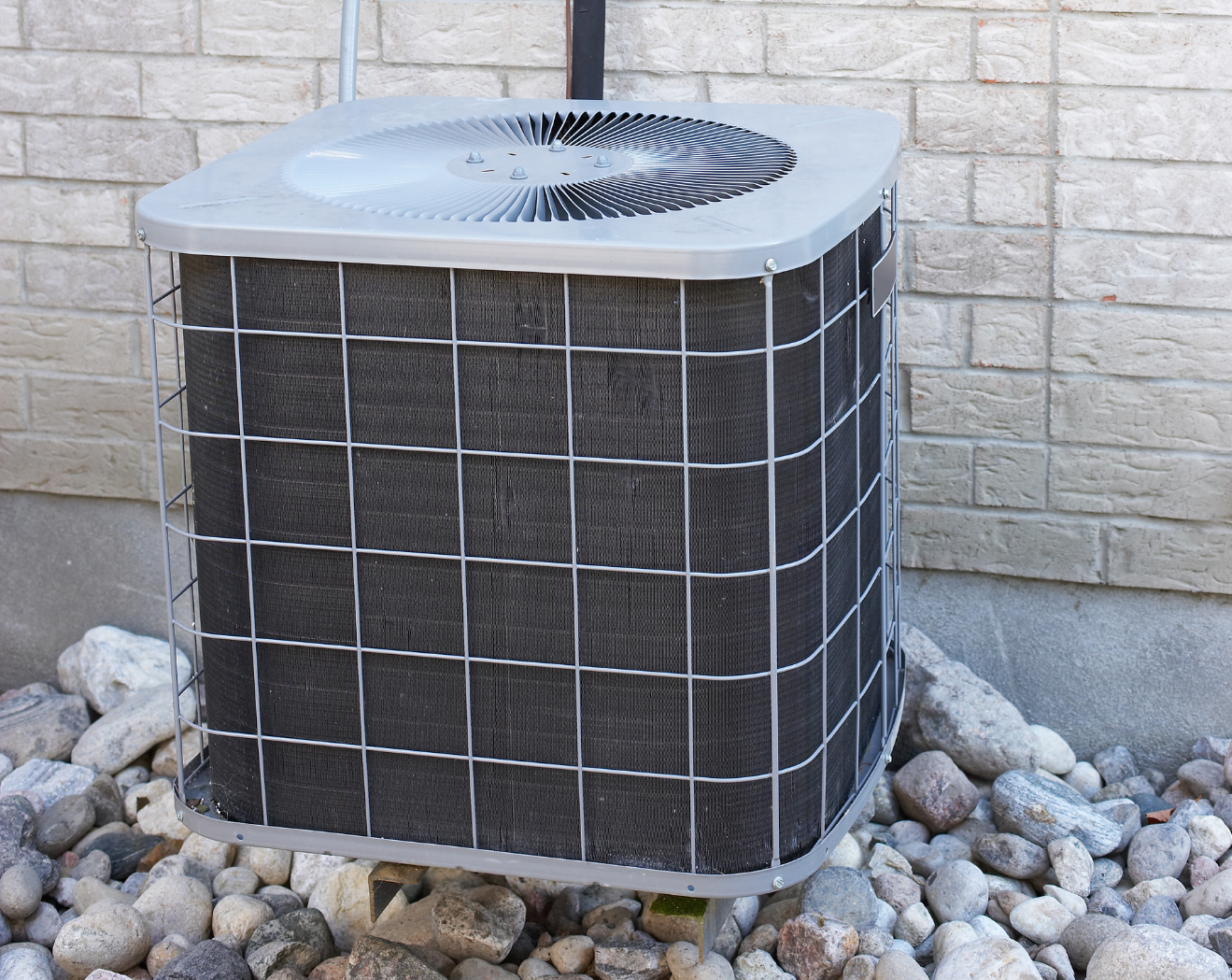HVAC unit with protective cage against stone wall
