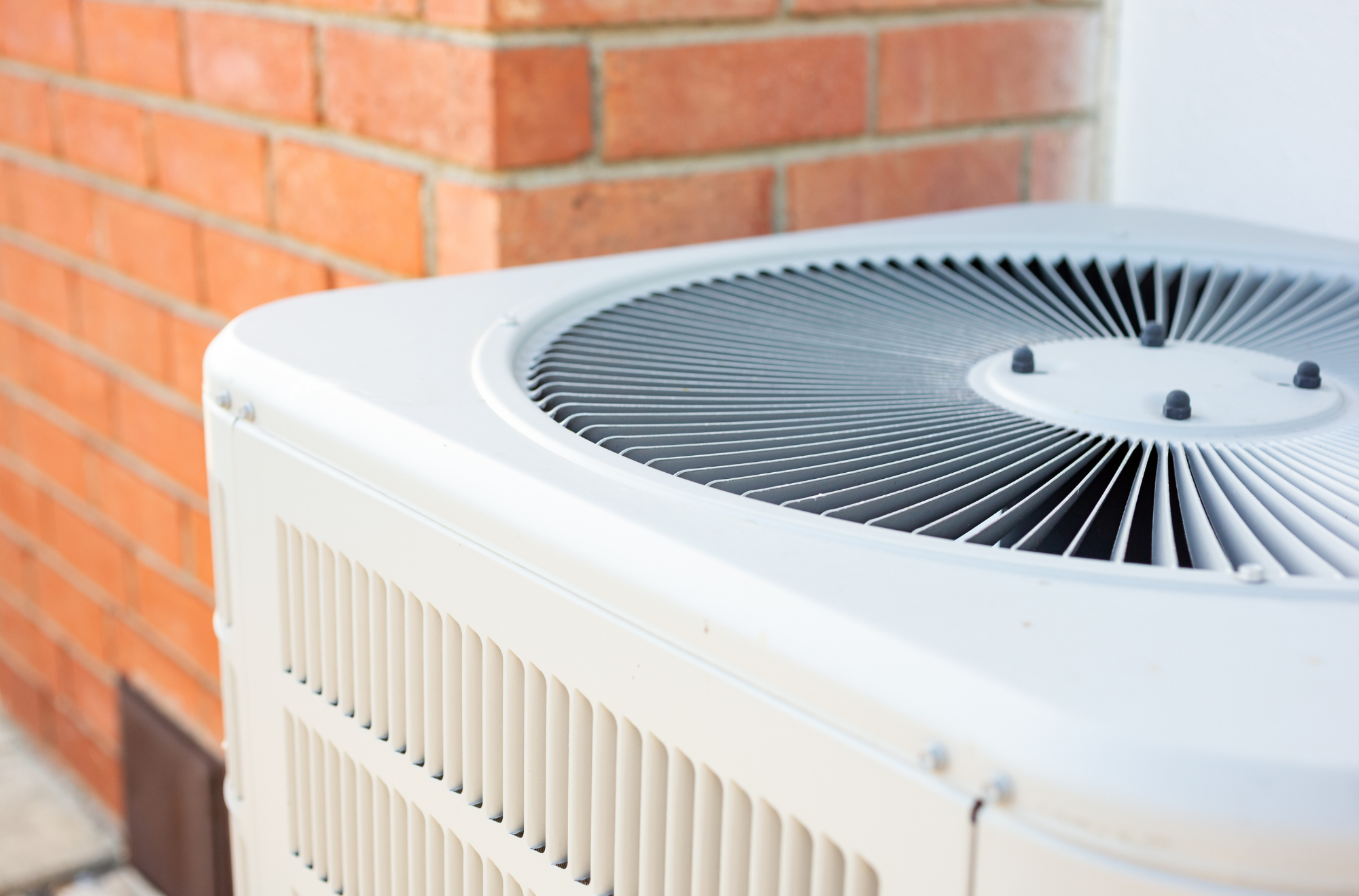 Modern HVAC unit installed against brick wall